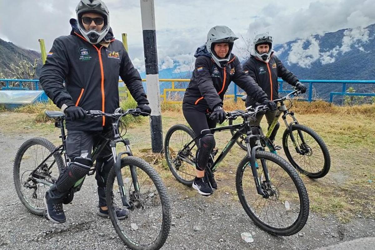 tiga orang berdiri dengan basikal mereka di atas jalan raya