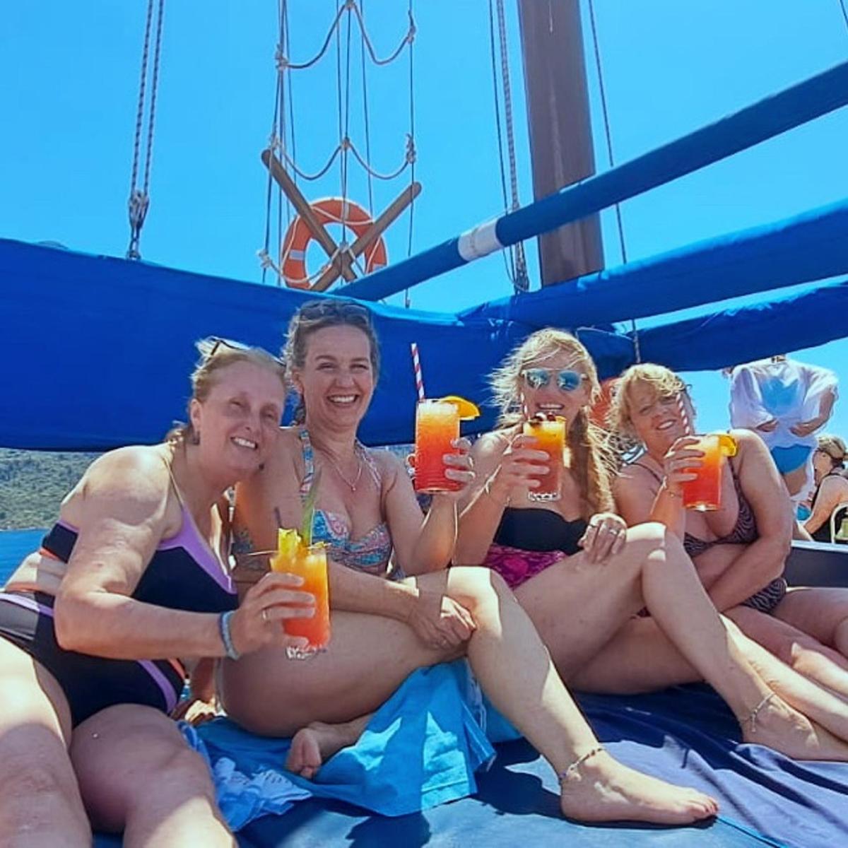 a group of women sitting on a boat drinking orange juice
