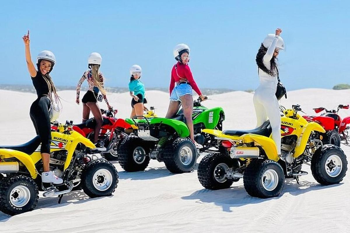 a group of people standing on atvs in the sand