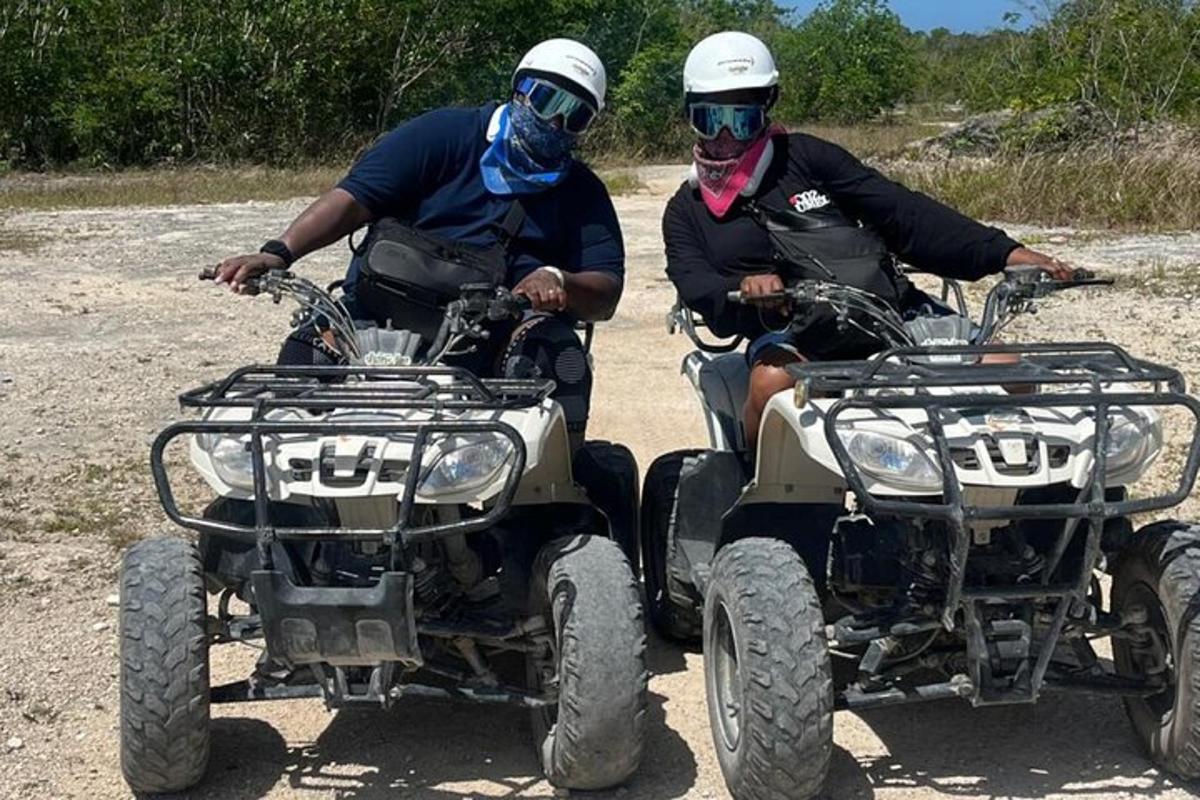 due persone che guidano un quad su una strada sterrata