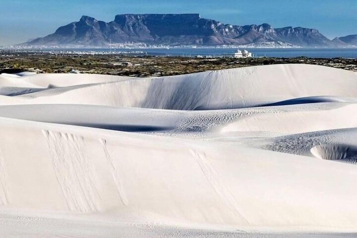 eine Gruppe von Sanddünen mit einem Berg im Hintergrund
