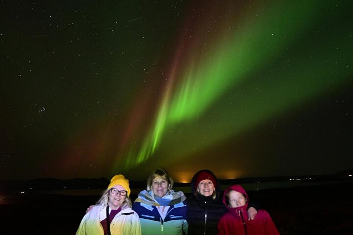 un gruppo di persone in piedi sotto l'aurora boreale