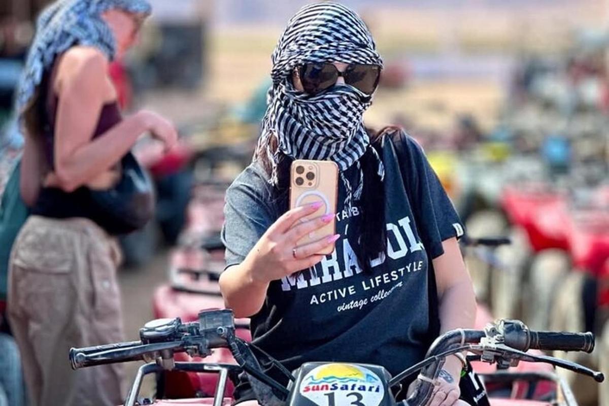 žena v šátku a dívající se na svůj mobilní telefon
