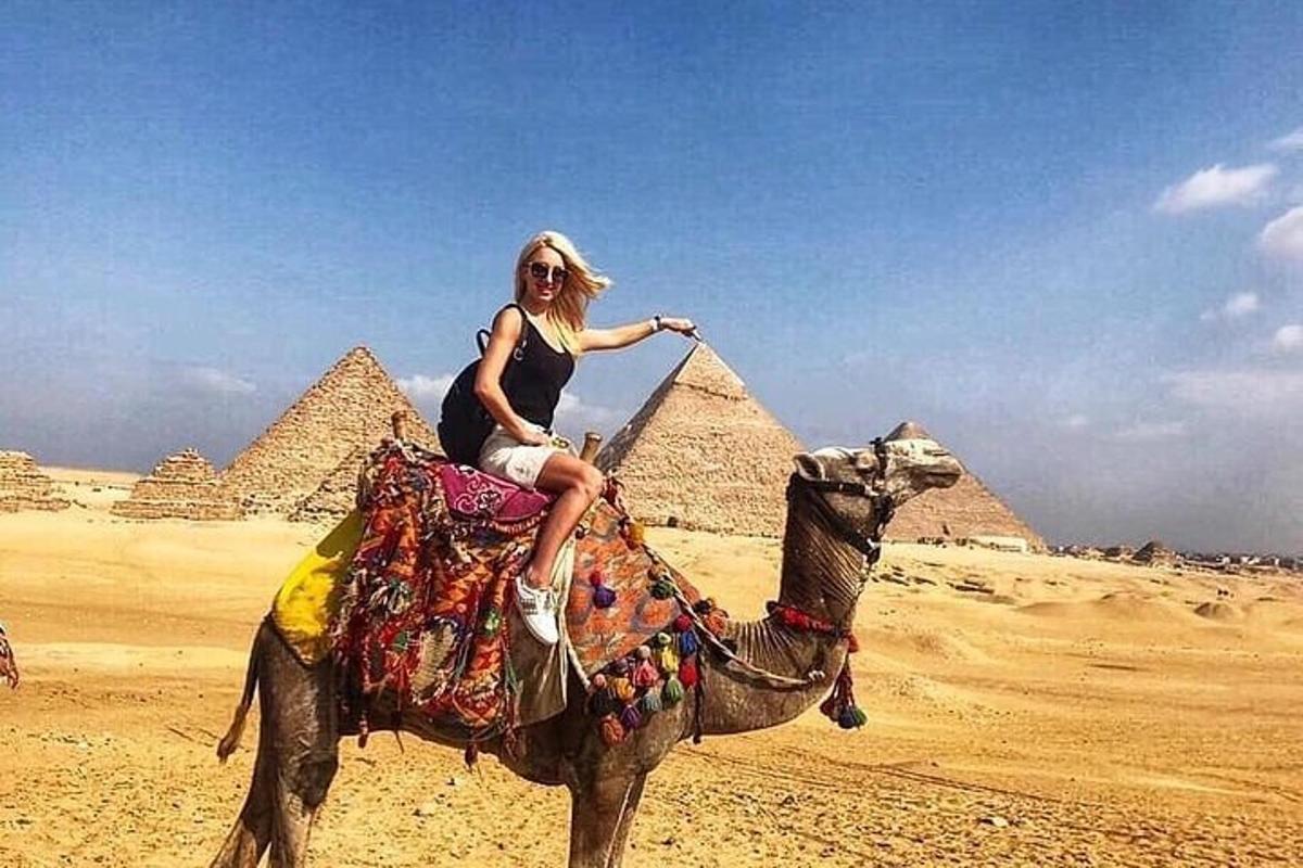žena jedoucí na velbloudovi před pyramidami