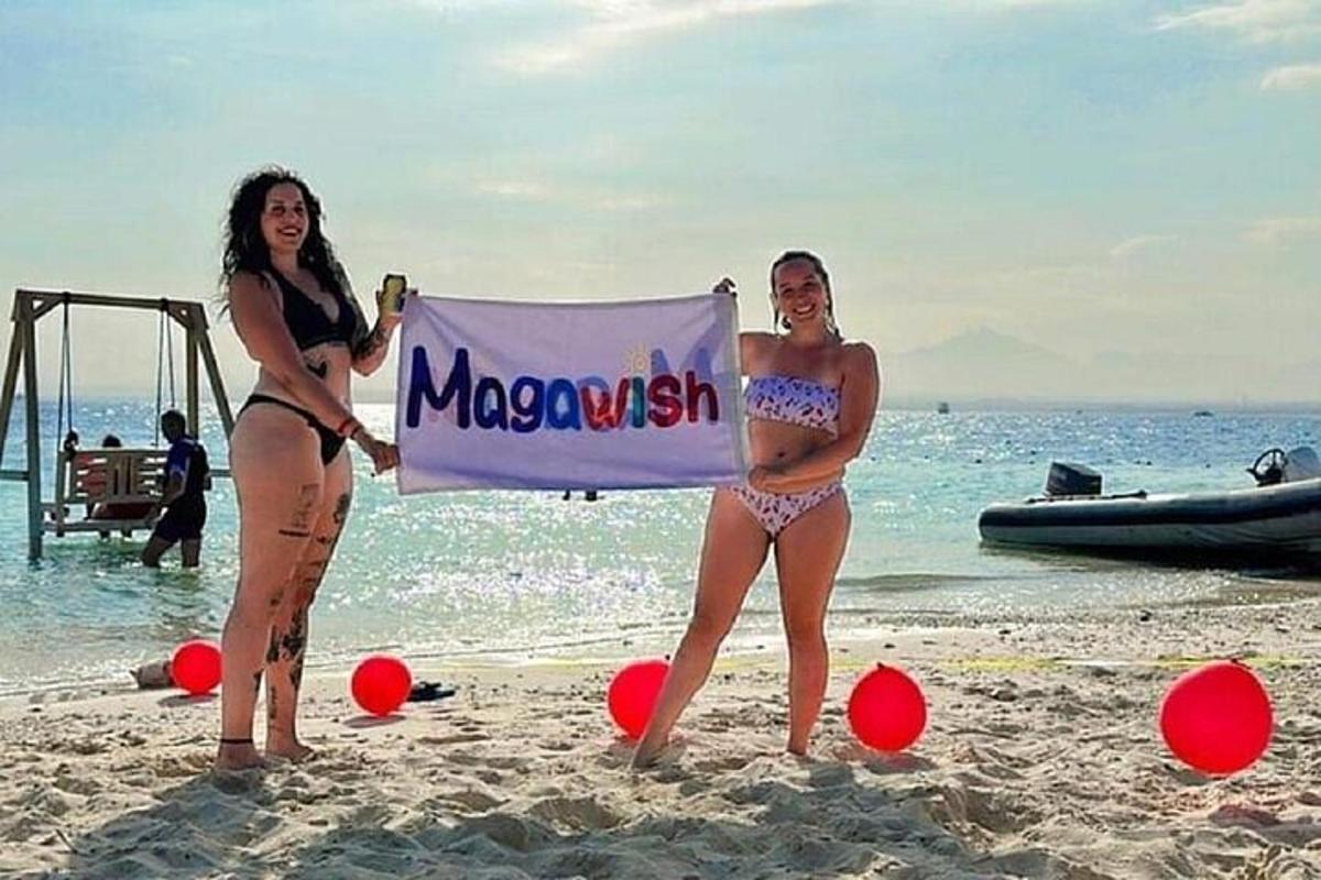 dua wanita dalam pakaian mandi berdiri di pantai dengan bendera