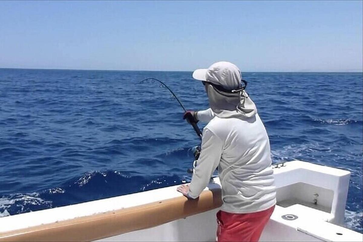 een man die op een boot staat en een hengel vasthoudt