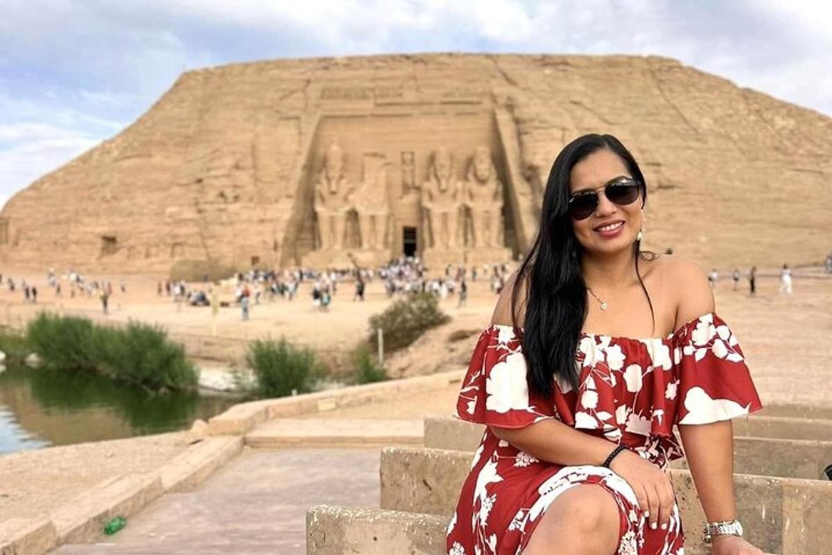 žena v červených šatech sedící před pyramidou