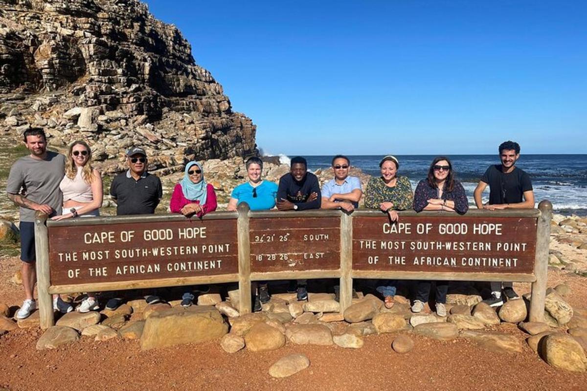 Un grupo de personas de pie detrás de un cartel en la playa.