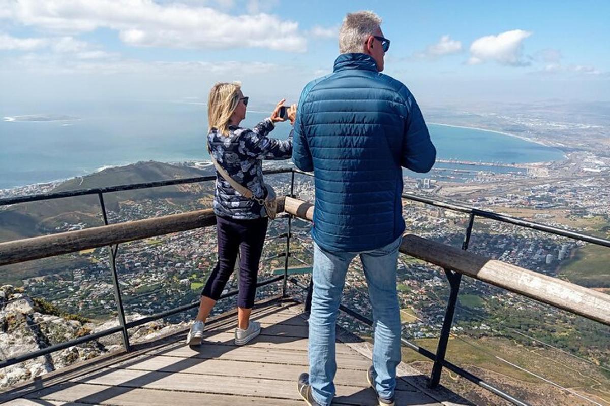 Maður og kona taka mynd af útsýninu af fjallstoppi