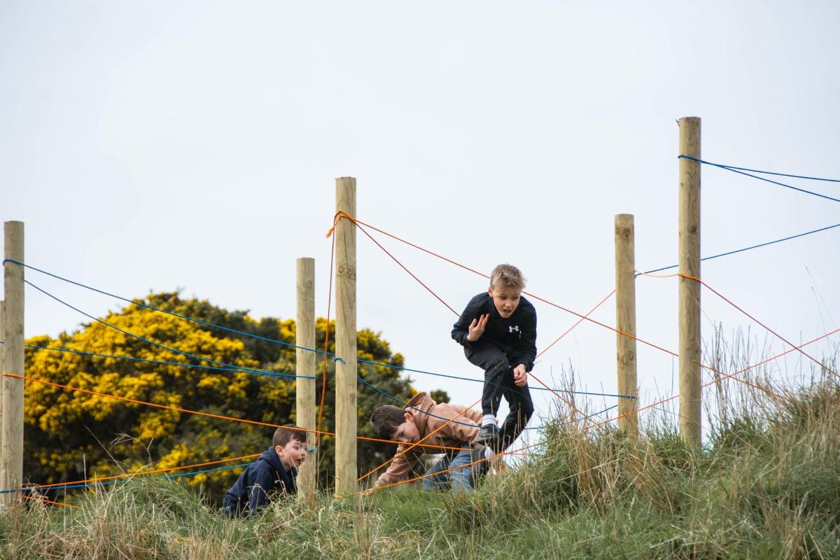 a group of men jumping over a fence