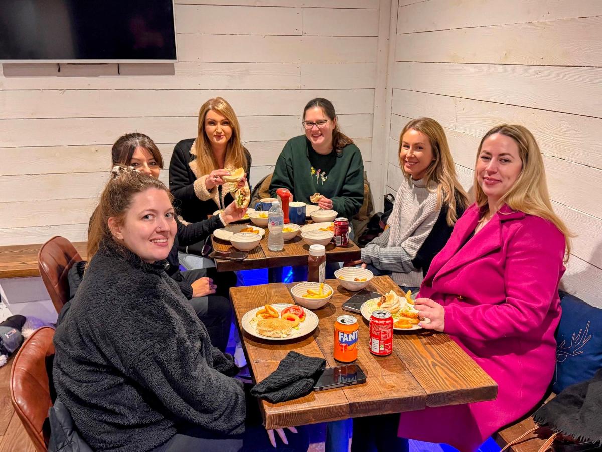a group of women sitting at a table eating food
