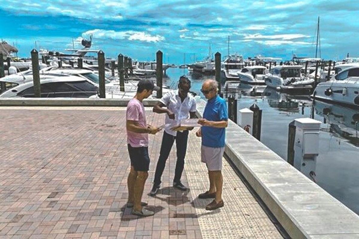 en gruppe på tre mænd stående ved siden af en marina