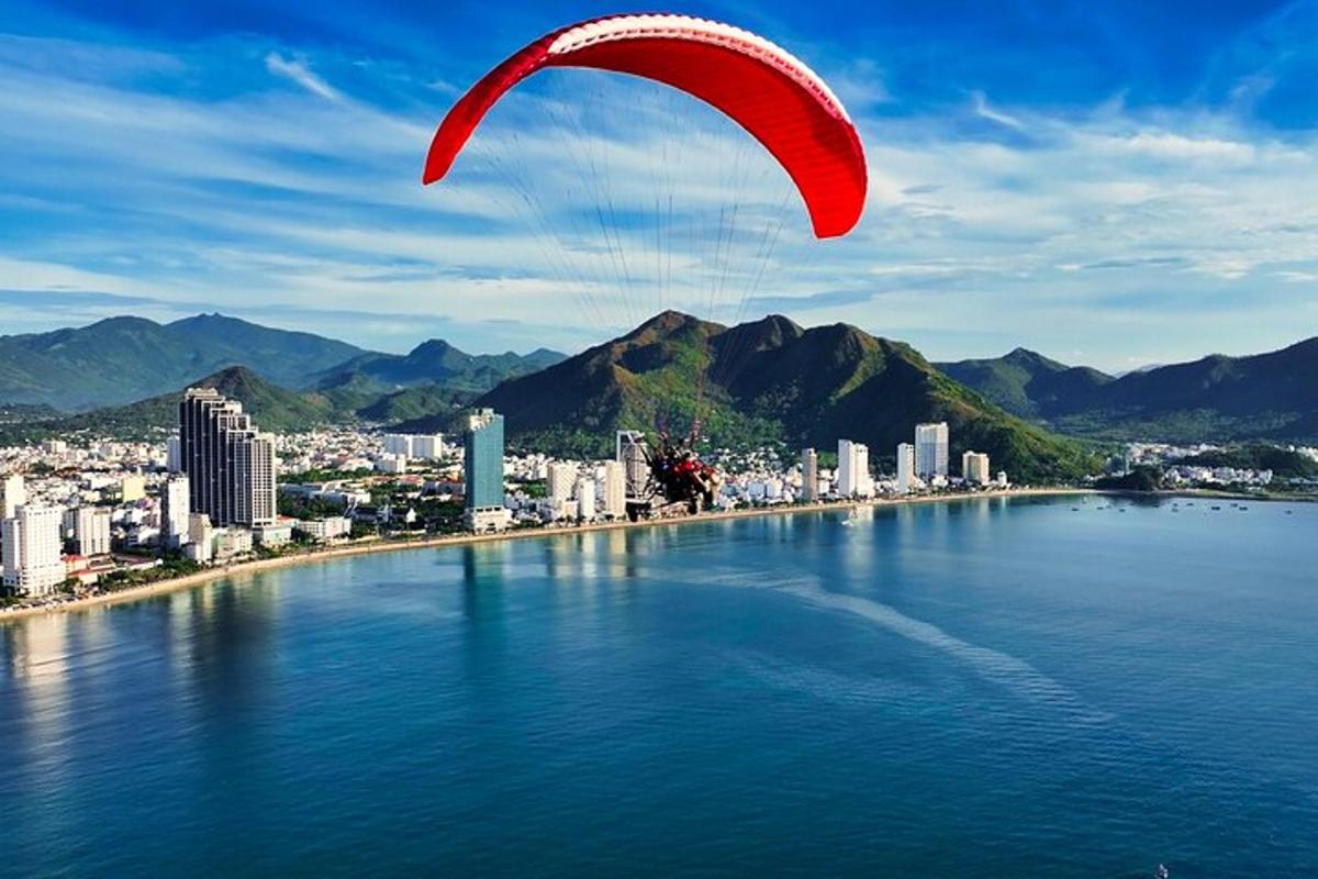Un paracaídas rojo volando sobre una gran masa de agua.