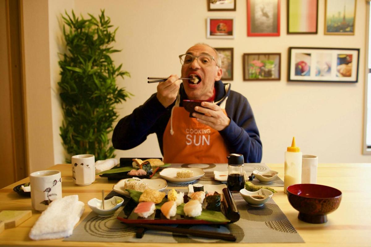 seorang lelaki makan sushi dengan penyepit di mulutnya