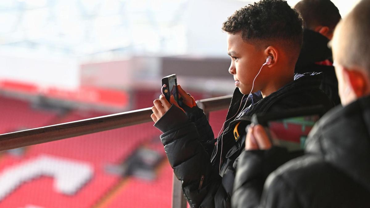 a boy with earphones and headphones looking at his cell phone