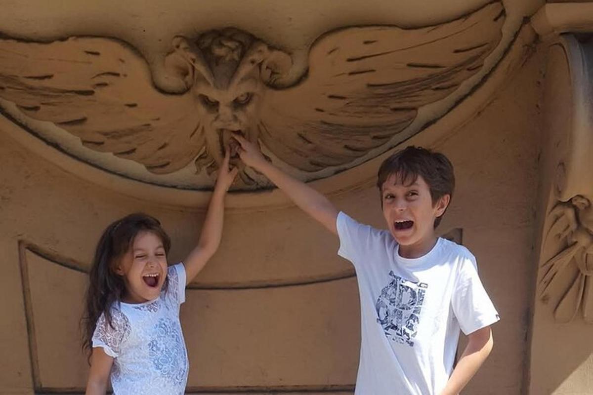 Un niño y una niña de pie frente a una escultura de un águila.