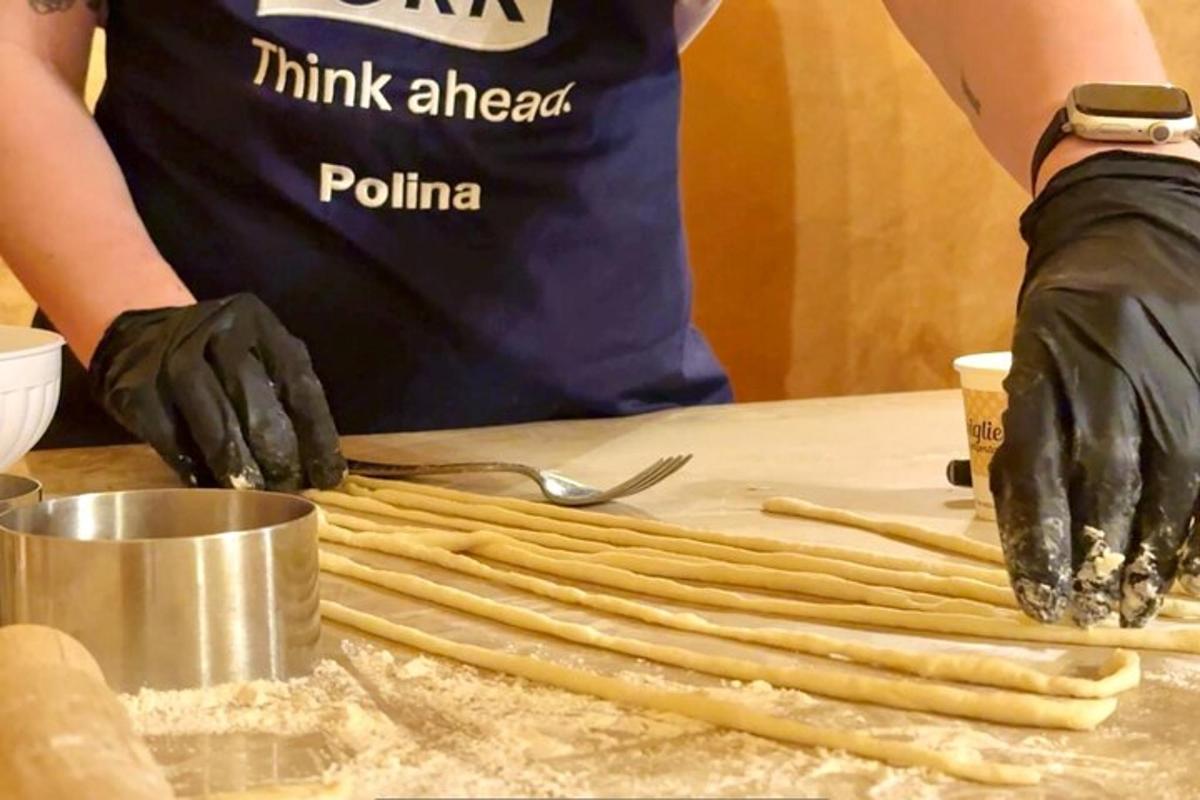 a person in black gloves kneading food on a table