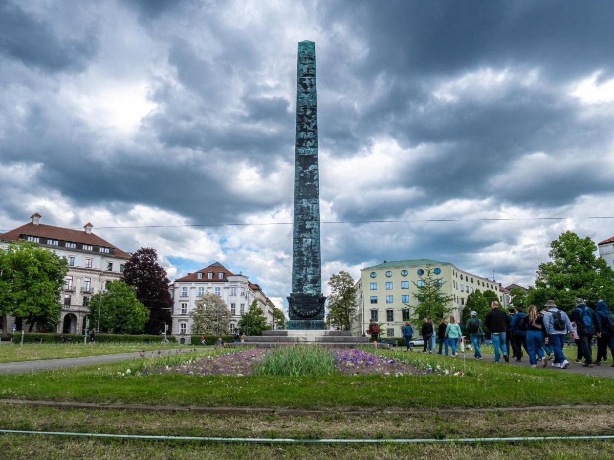 a monument in a park with people walking around it