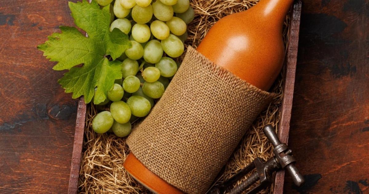 a bottle of wine next to a bunch of grapes