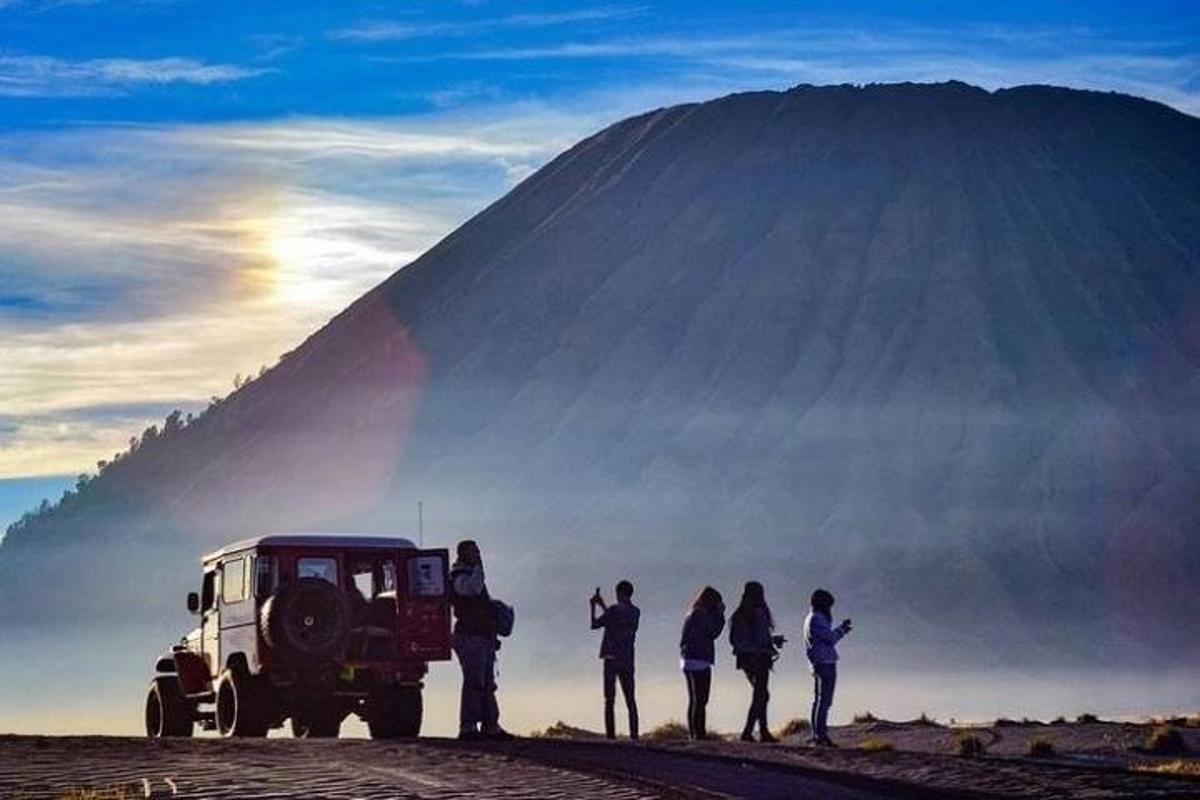 a group of people standing around a truck in front of a mountain