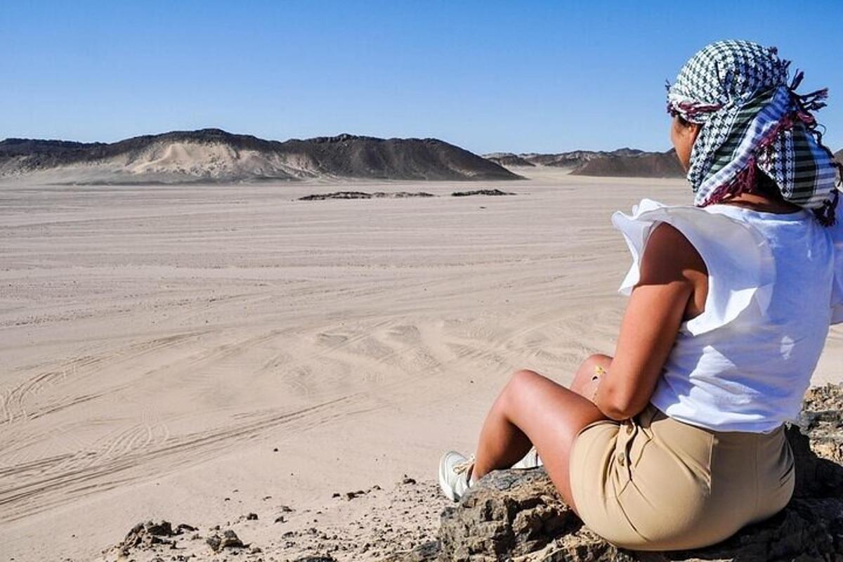 una donna seduta su una roccia nel deserto