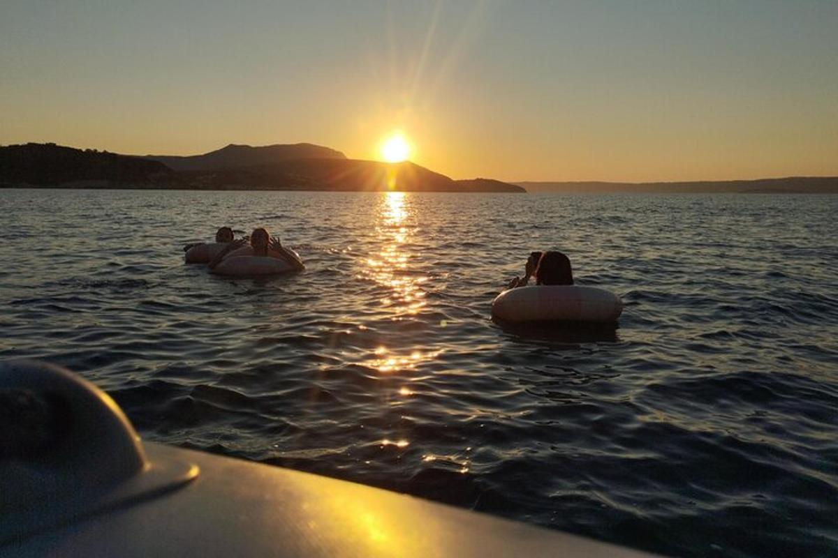 drie mensen zitten bij zonsondergang op tubes in het water