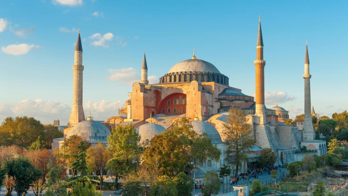 a building with two mosques with trees in front of it