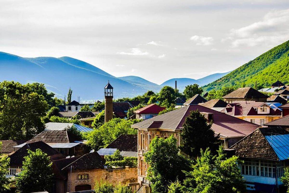 a town with a clock tower and mountains in the background