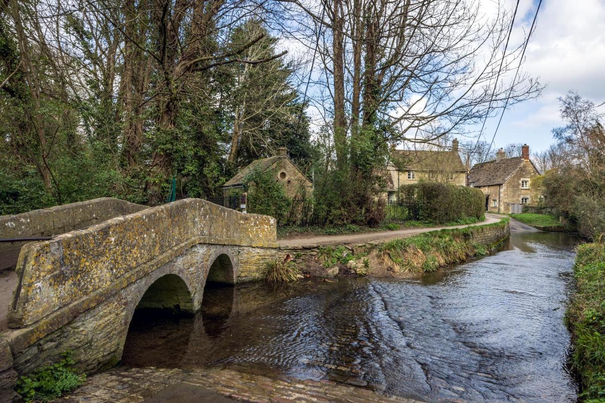 eine Steinbrücke über einen Fluss in einem Dorf