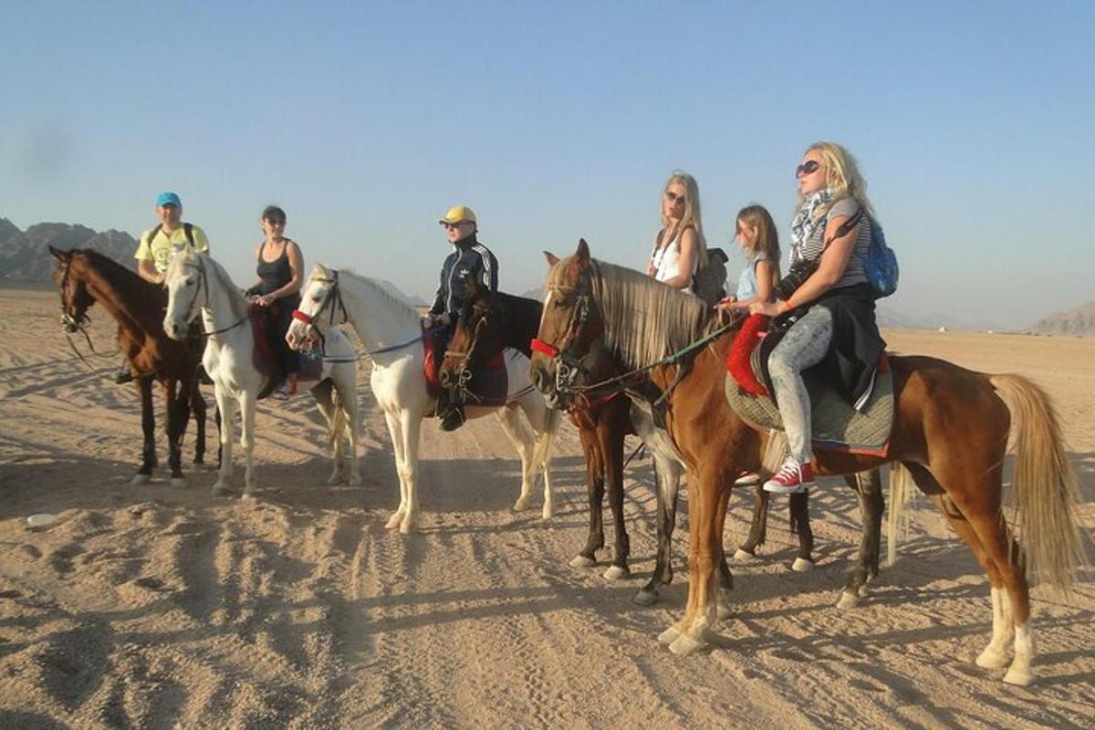 a group of people riding horses in the desert