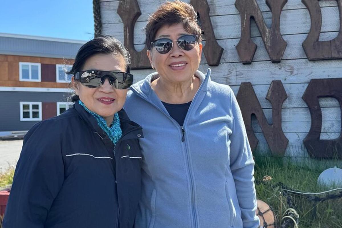 two women standing next to each other in front of a building