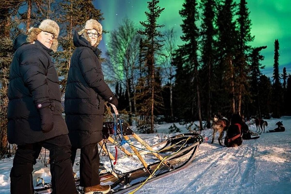 to personer står i snøen med en kjelke