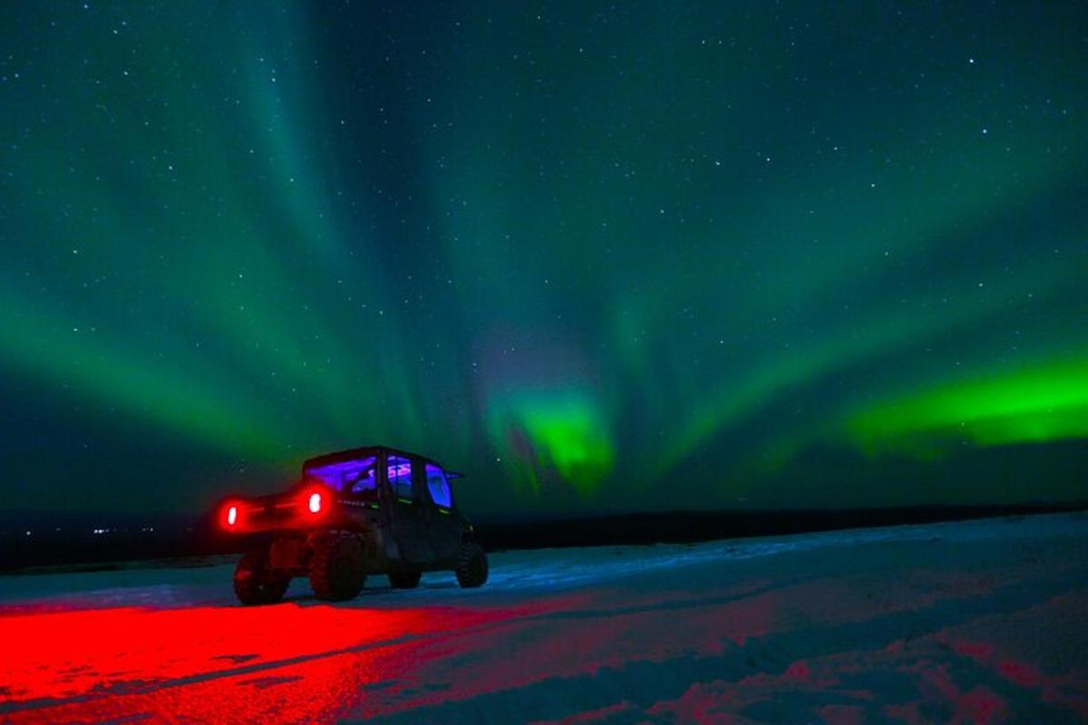 un jeep conduint sota l'aurora boreal
