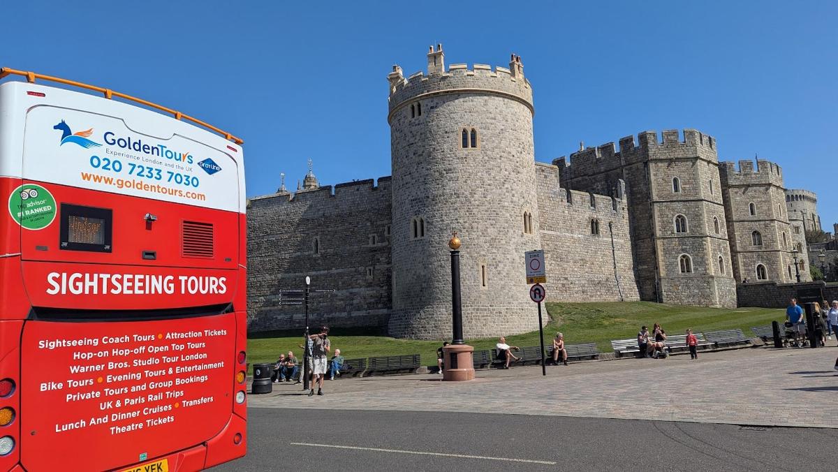 a red double decker bus parked in front of a castle