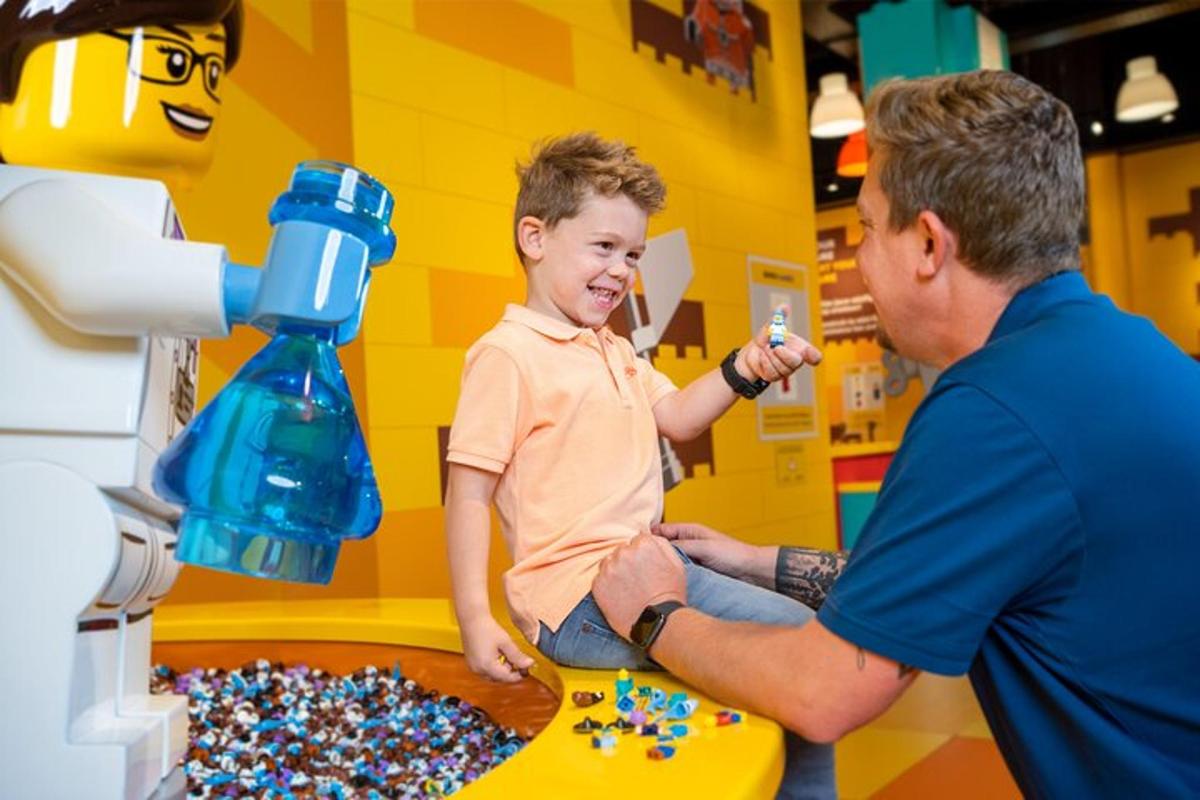 en mand hjælper en ung dreng med at lege med lego