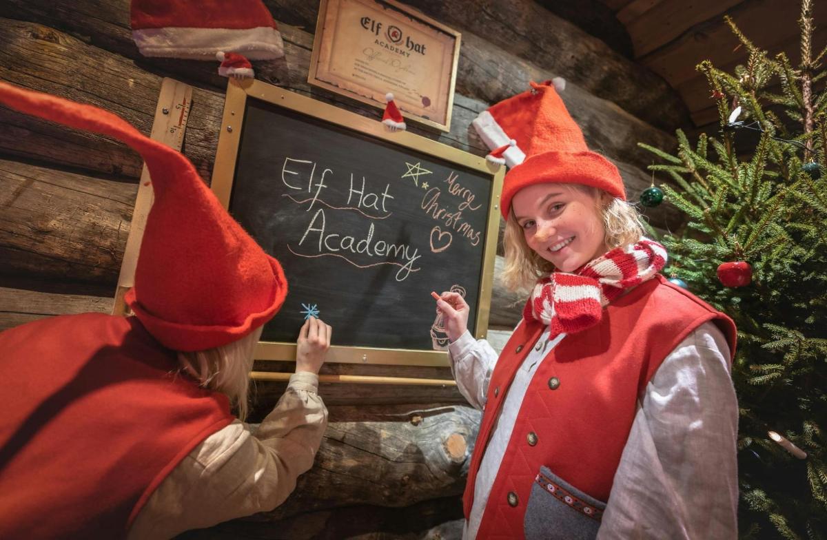 a girl and a boy in elf costumes standing in front of a blackboard