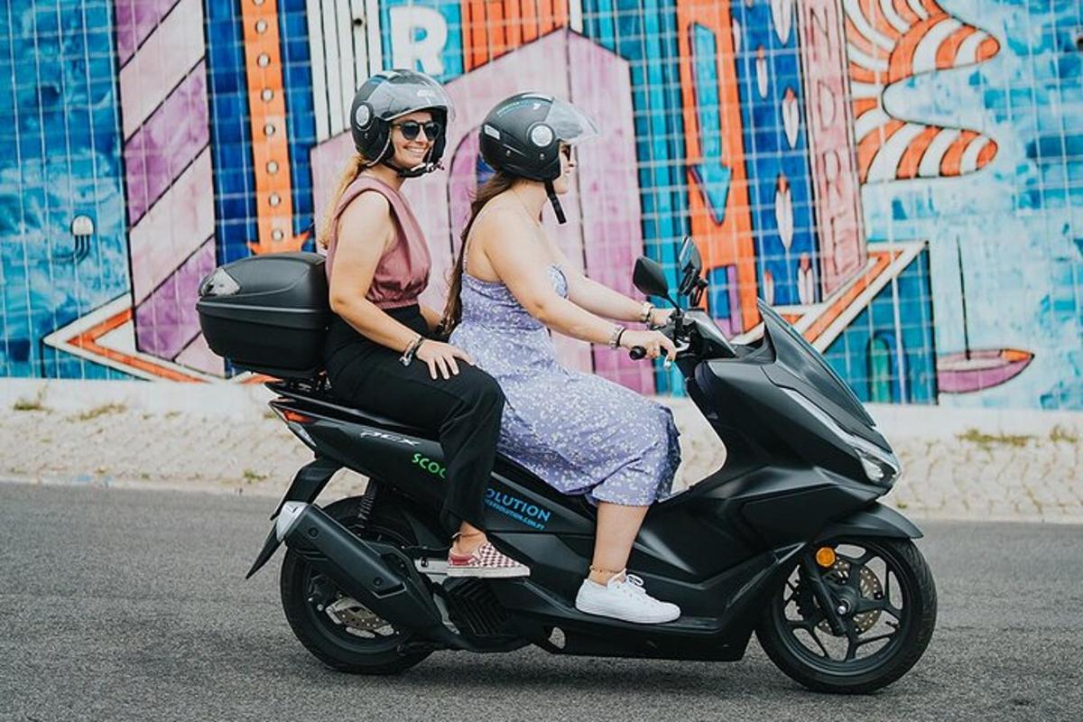 Tvær konur keyra á vespu á götunni