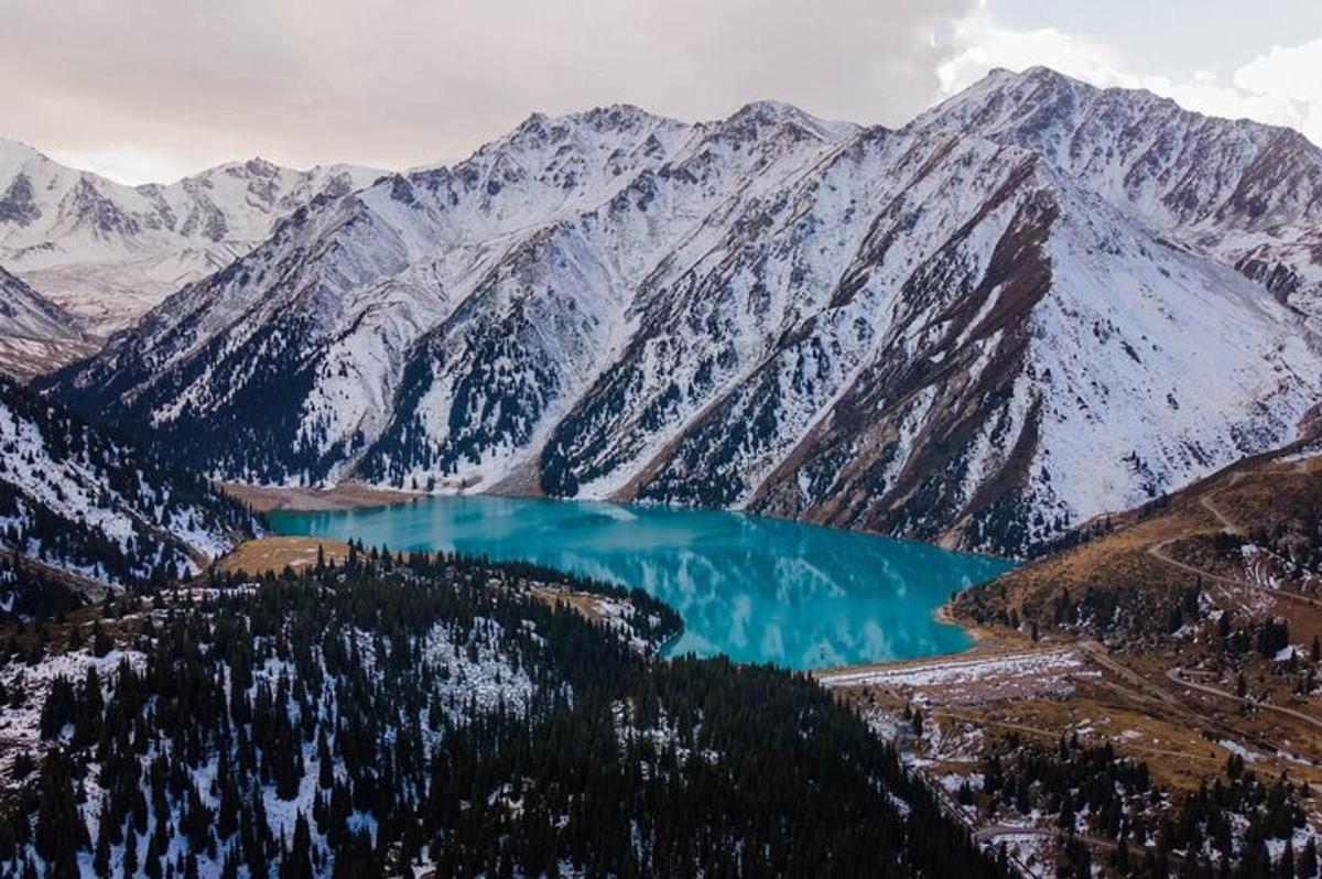 an aerial view of a mountain lake with snow covered mountains