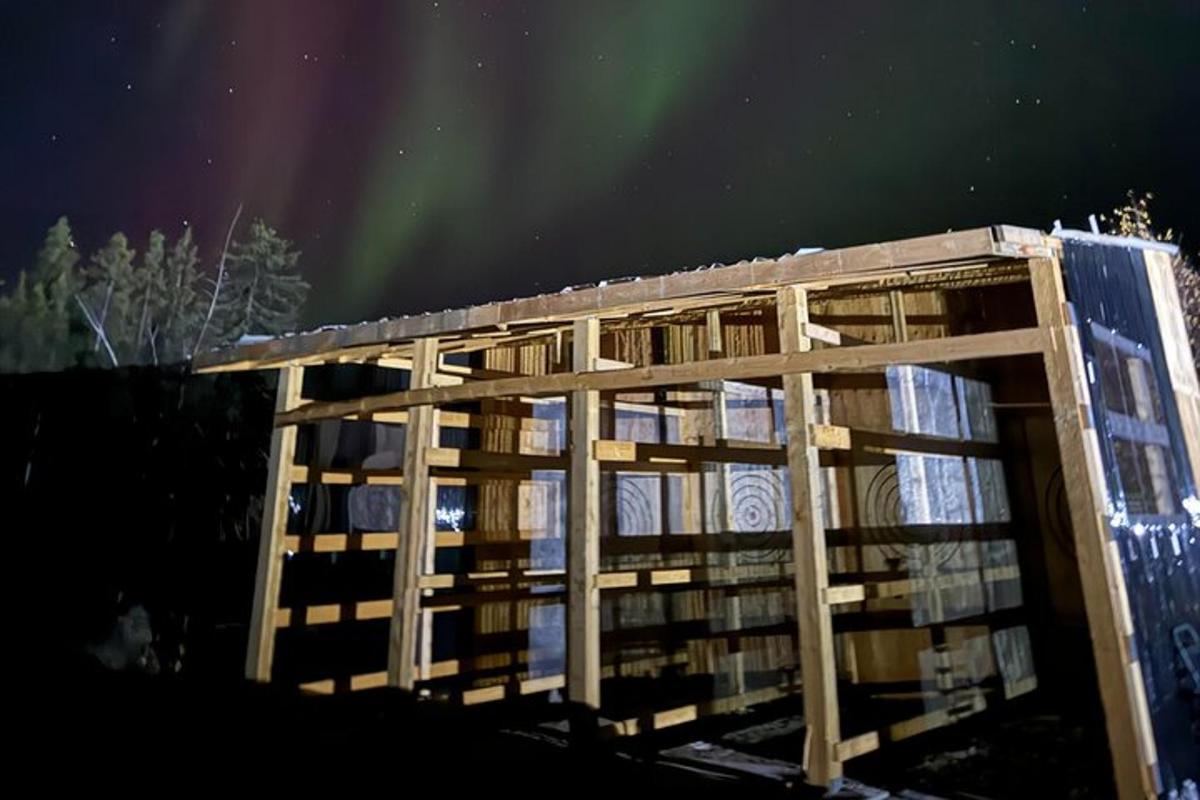 a wooden building under the aurora borealis