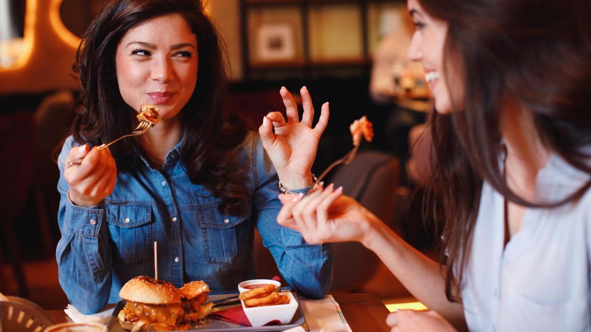 two women sitting at a table eating food