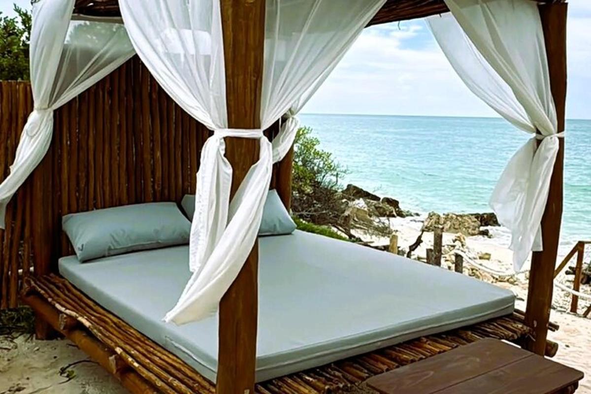 a bed on the beach with the ocean in the background
