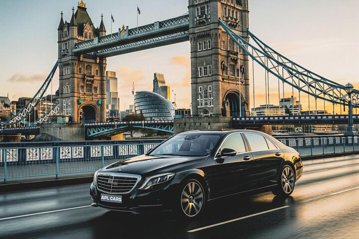 a black car driving in front of the tower bridge