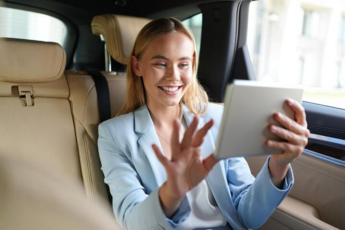 a woman sitting in the back seat of a car using a tablet