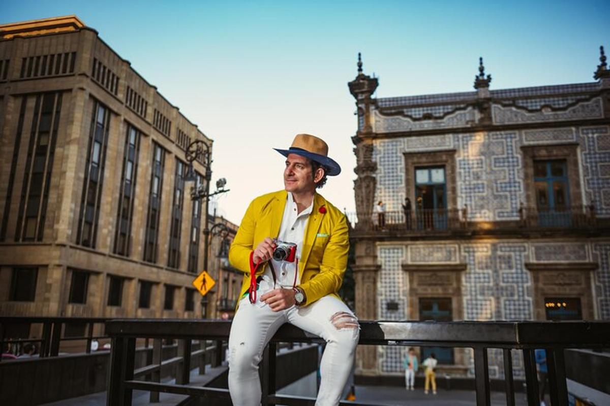 a man in a hat sitting on a fence with a camera