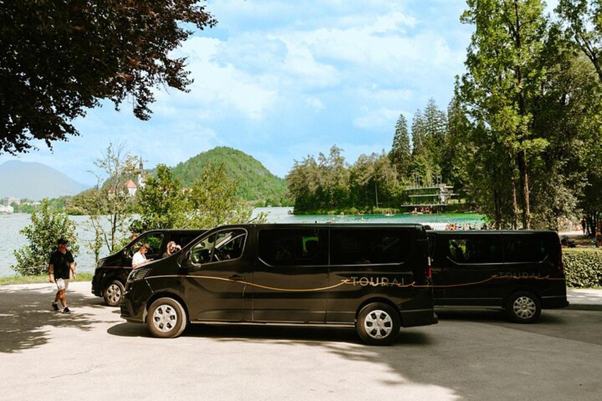 two black vans parked in a parking lot next to a lake