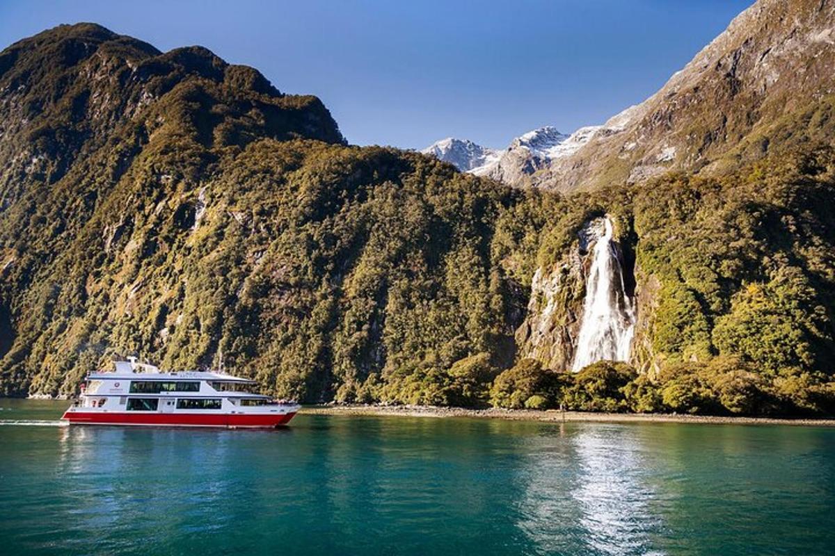 a boat in the water next to a waterfall
