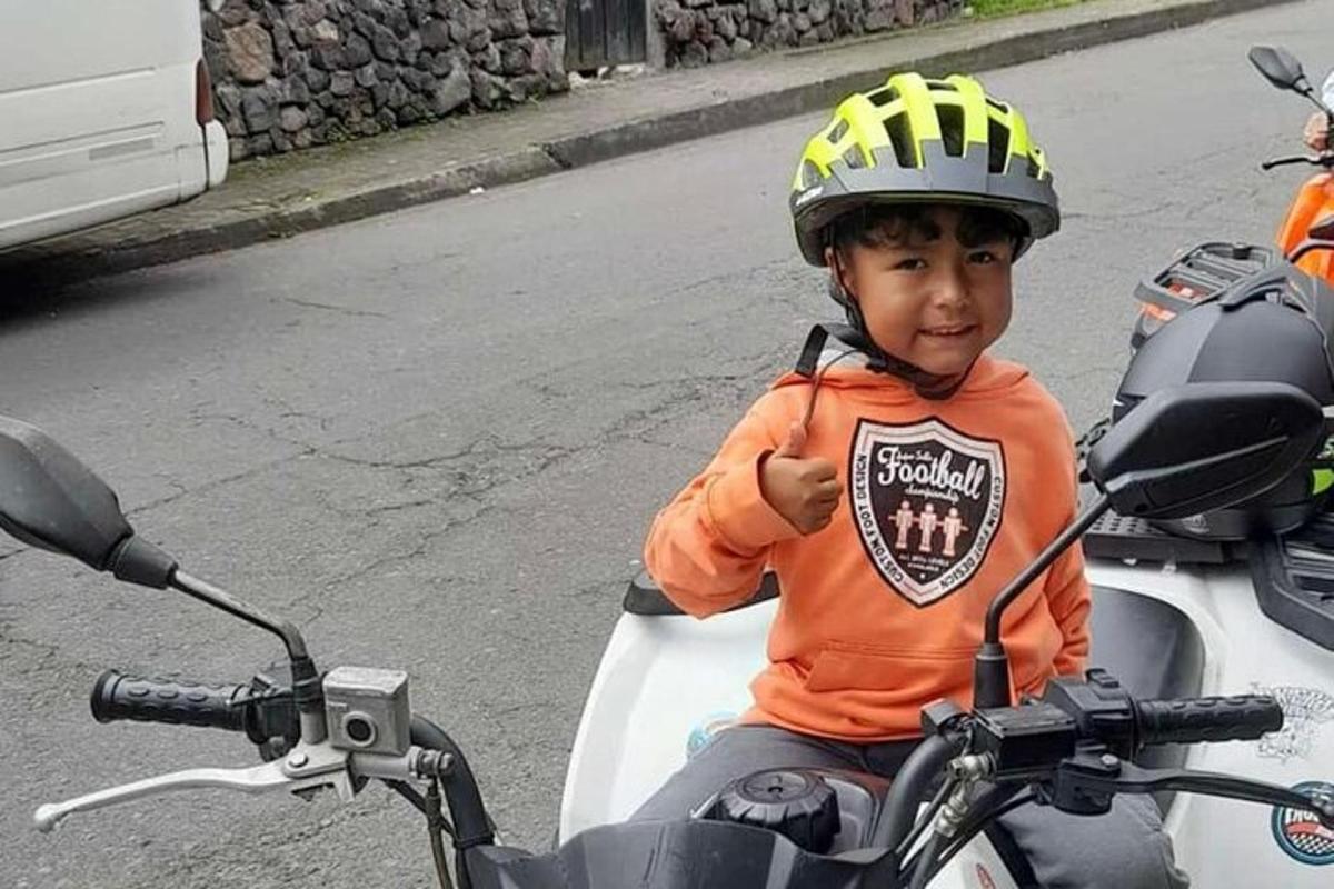 a young boy wearing a helmet sitting on a motorcycle