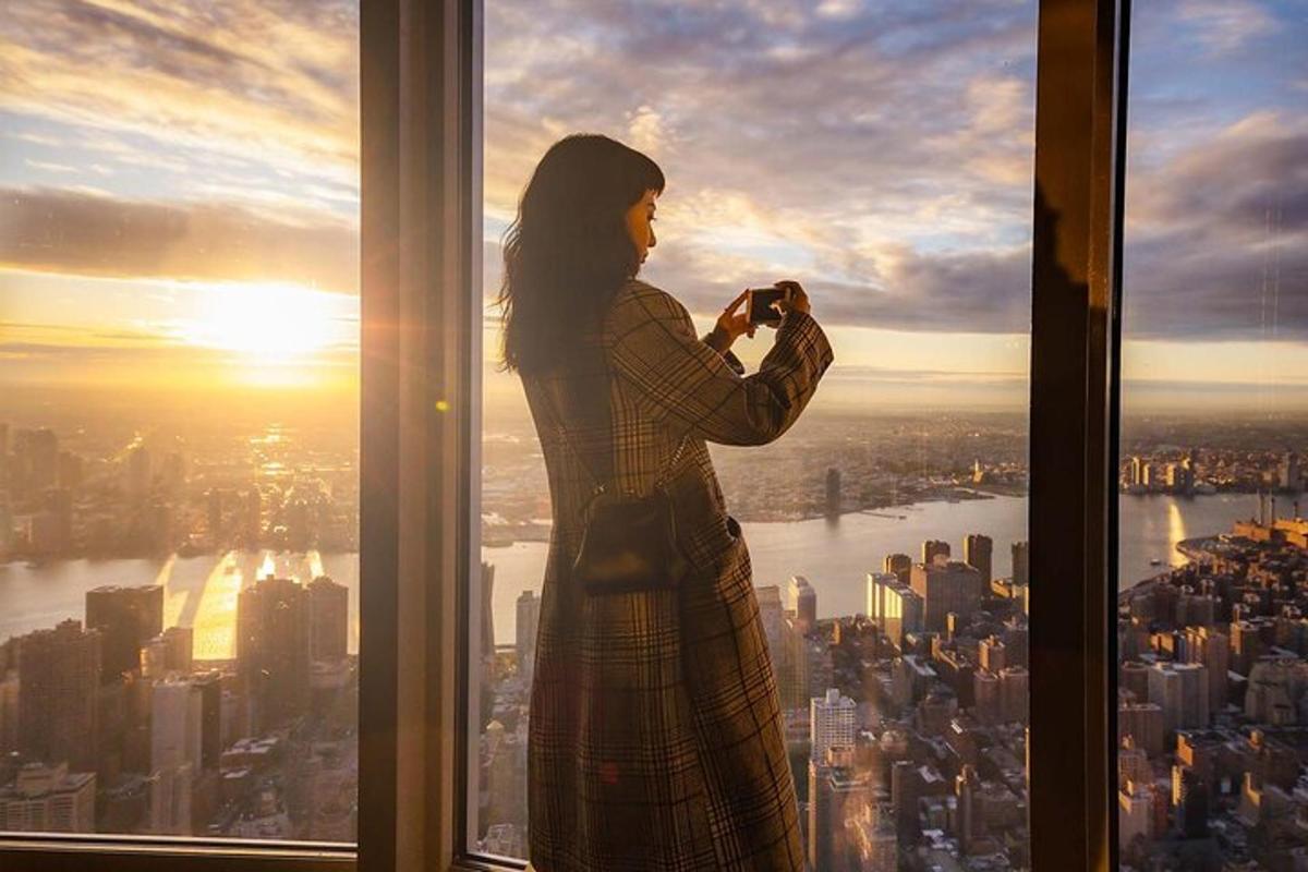 a woman standing in a window taking a picture of the city