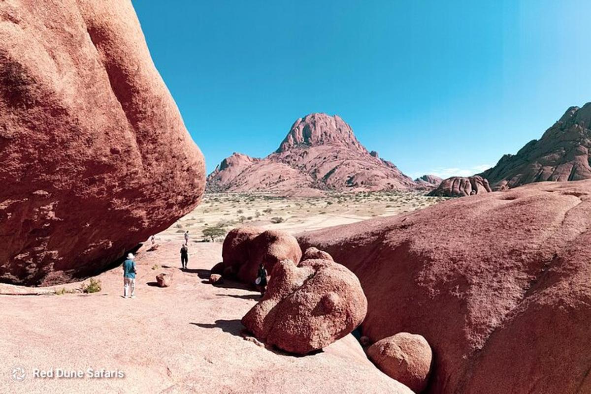 a group of people standing next to some big rocks