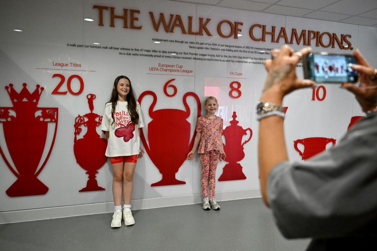 a man taking a picture of two girls in front of a wall of dresses